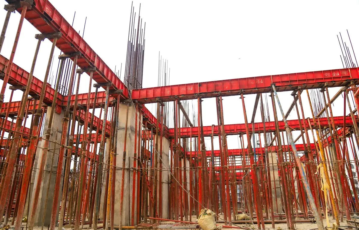 A building under construction with lots of red scaffolding (stock photo)