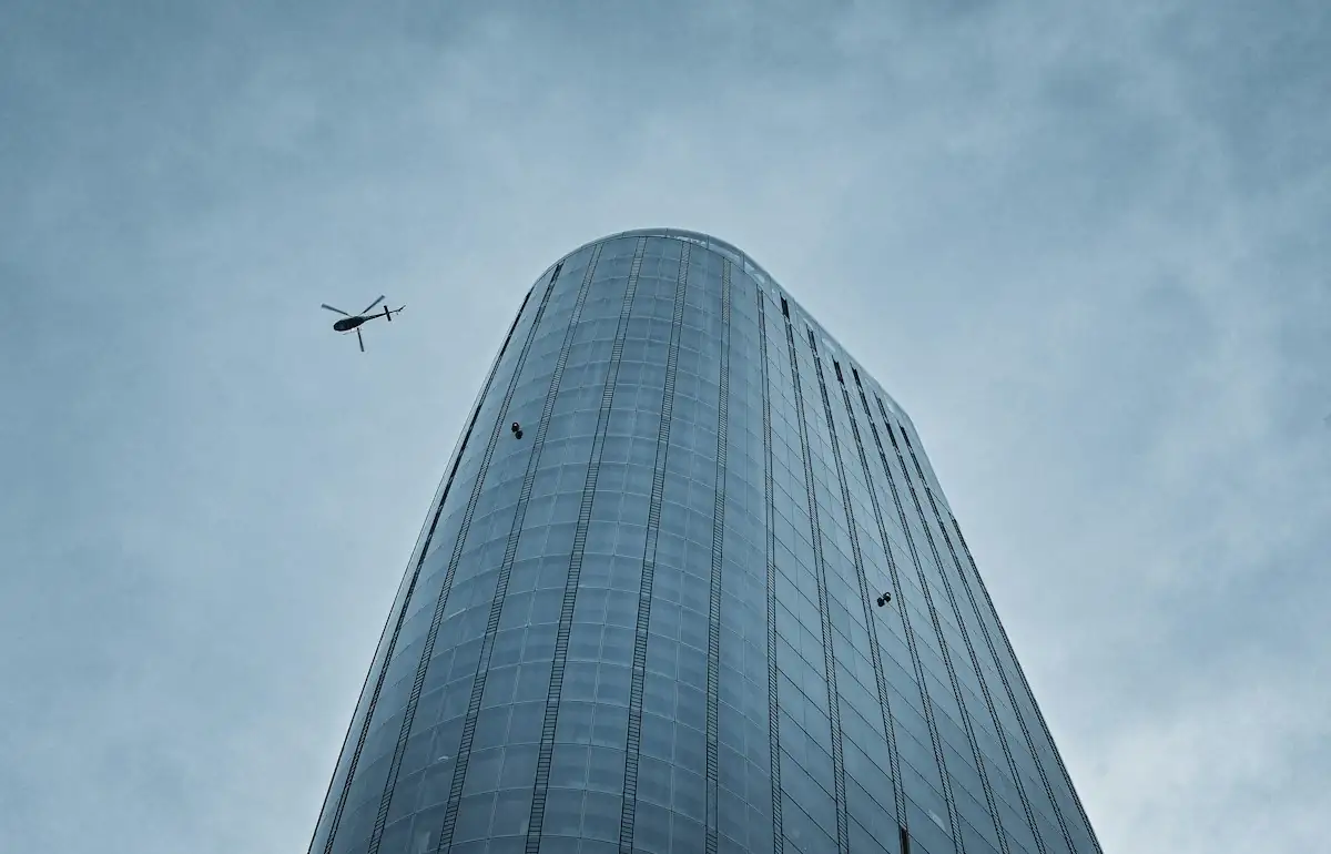 A very tall building with a helicopter flying in the sky (stock photo)