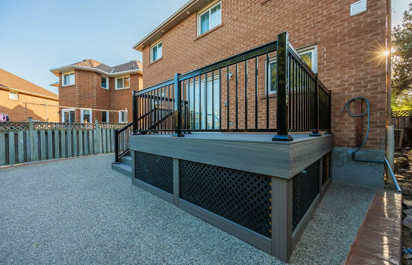 Finished elevated deck with a metal guard rail beside a brick home (stock photo)