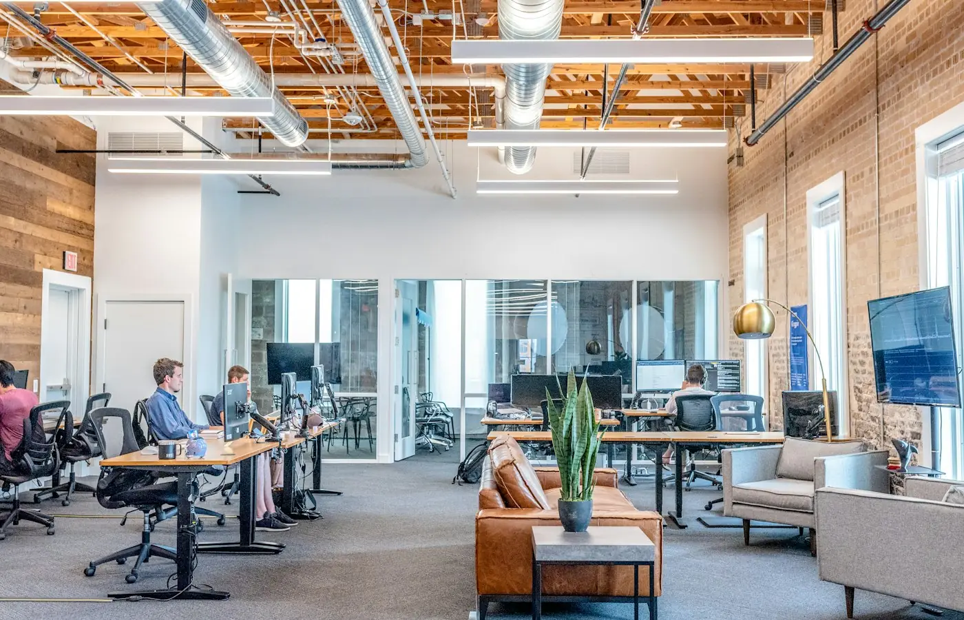 Finished open-plan office with exposed ceiling and brick walls after a tenant build-out (stock photo)
